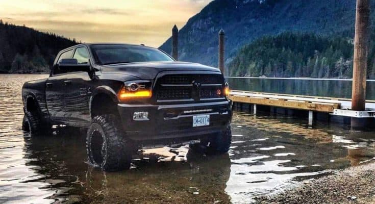 Black Dodge Ram sitting in shallow water off road