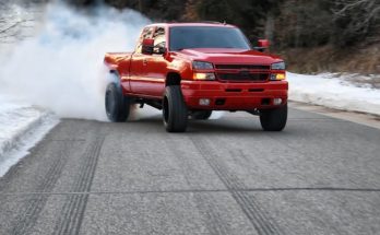 Red Chevy Silverado Duramax driving down the road in the winter