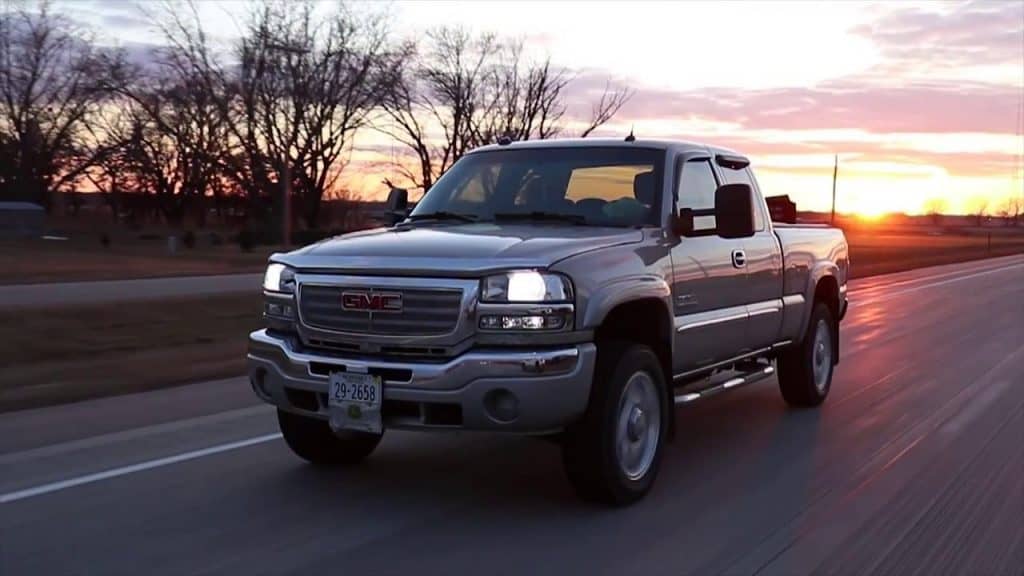 Grey GMC Sierra driving down the highway at sunset